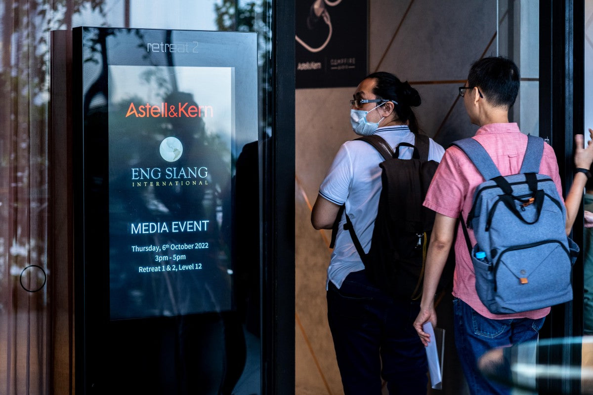 Attendees entering through the door to the Astell&Kern SP3000 and Odyssey media launch with details of the event being displayed on a digital screen to the left of the door.