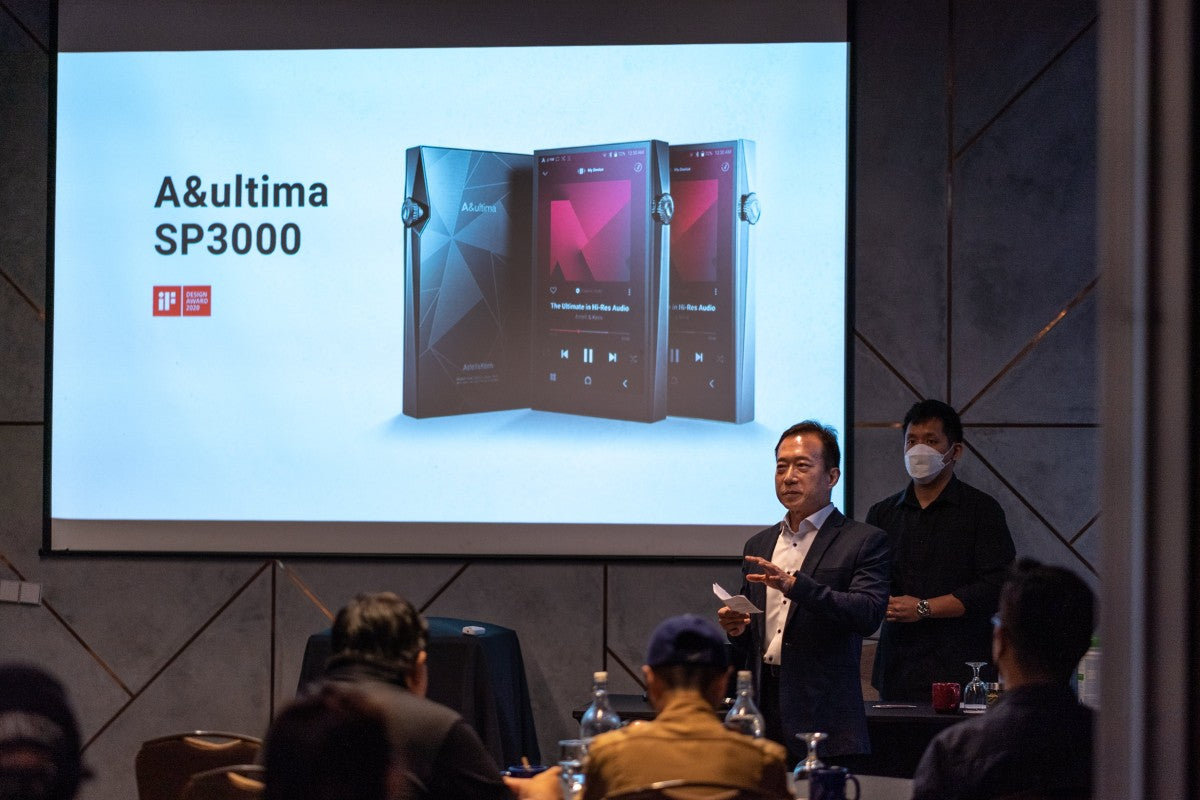 A presenter engaging with the audience with the Astell&Kern A&ultima SP3000 product image is displayed on the big screen.