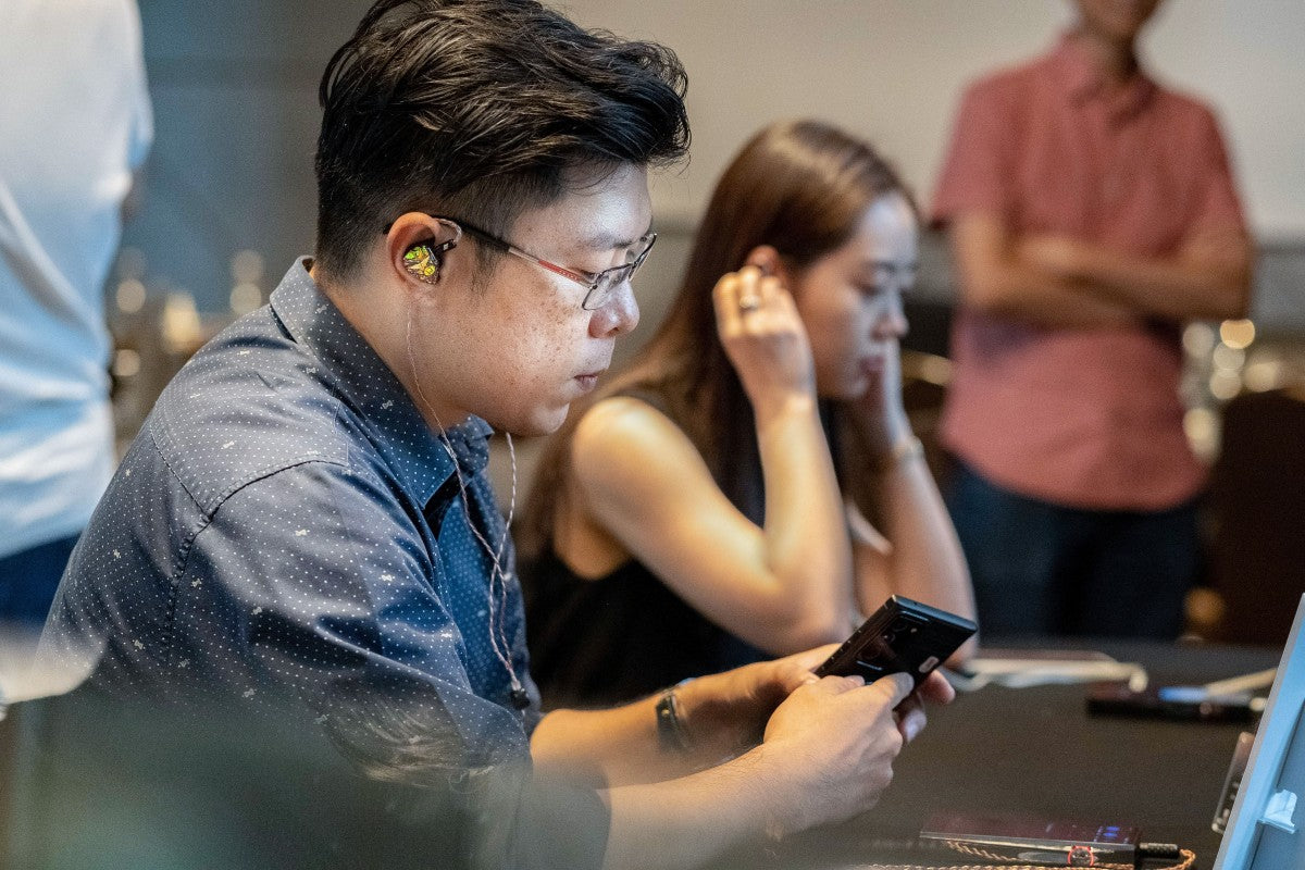 A man wearing glasses auditioning the Astell&Kern Odyssey in-ear monitors.
