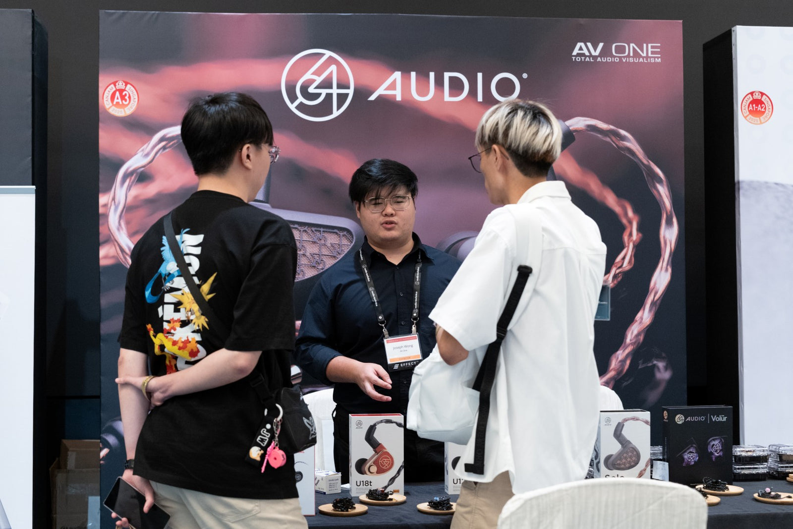 Exhibitor and attendees interacting at the 64 Audio booth managed by AV One at CanJam Singapore 2025 event.
