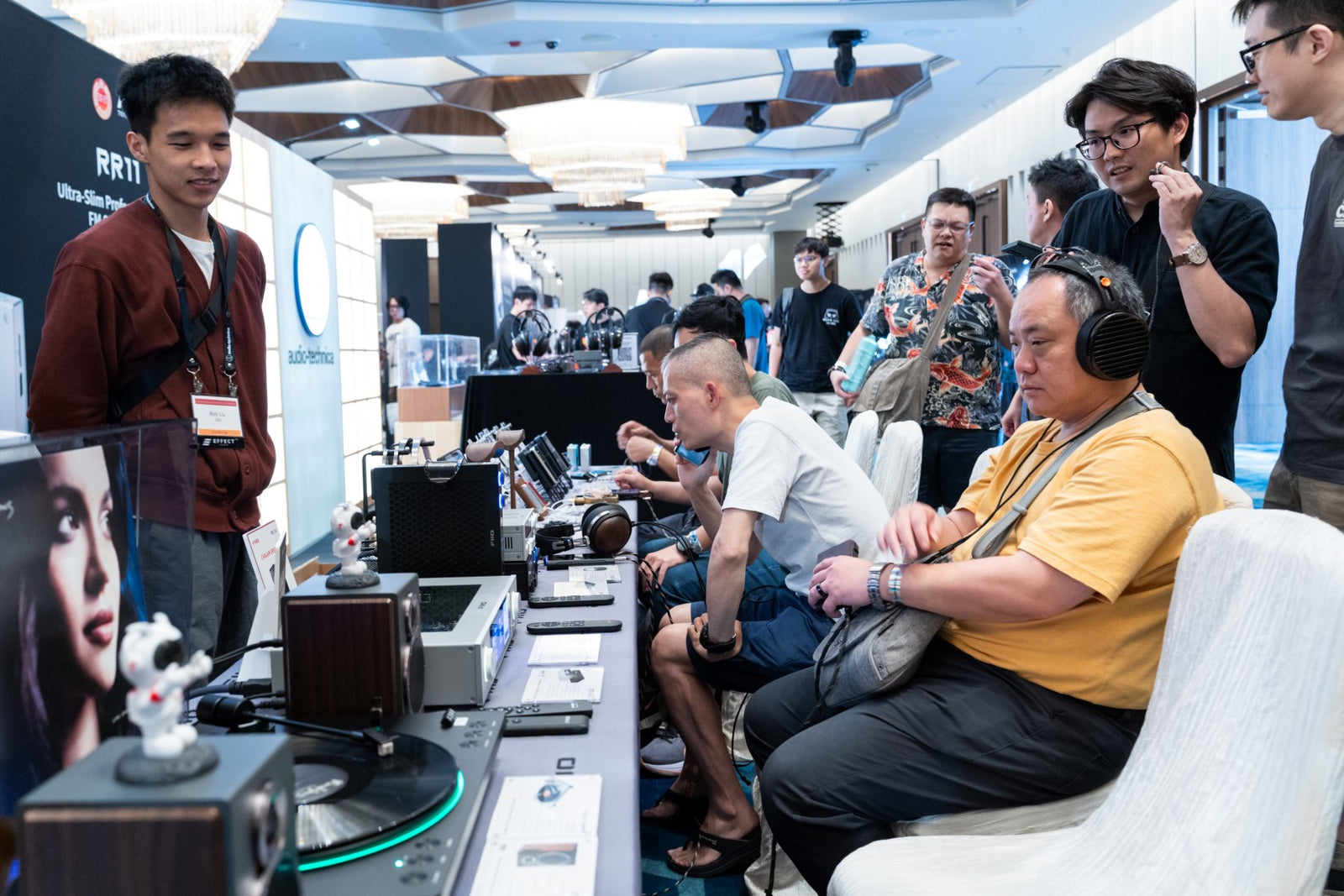 Attendees interacting with products at the FiiO booth, overseen by an exhibitor at CanJam Singapore 2025 event.