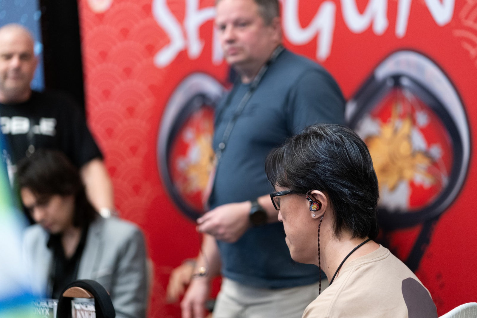 A close-up shot of an attendee auditioning an in-ear monitor at the Noble Audio booth during the CanJam Singapore 2025 event.