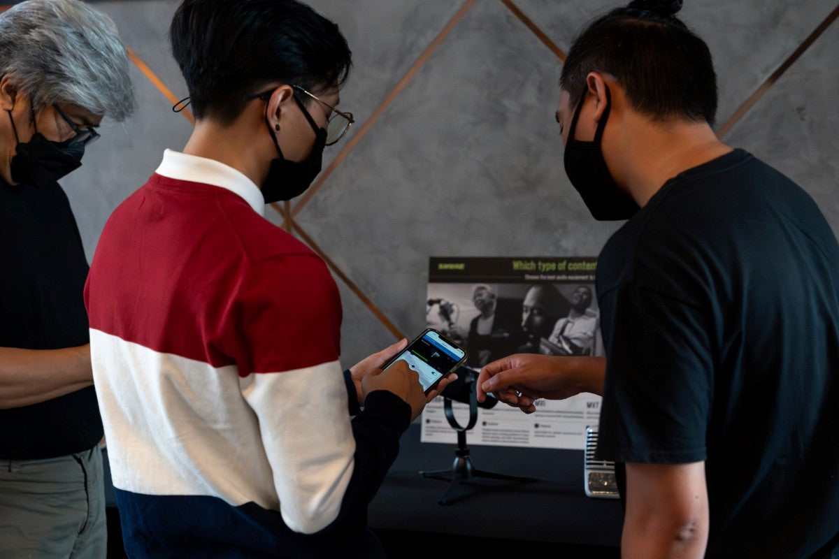 Two men interacting with one showing something on his mobile phone at the Shure SE846 Gen 2 and SE215 Special Edition Purple media launch event.
